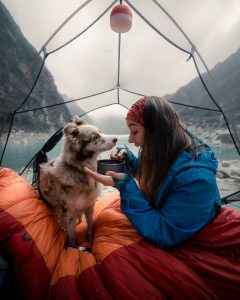 woman inside tent camping with dog