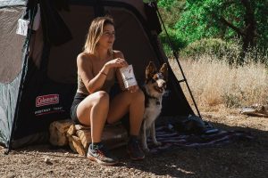 woman and dog sitting outside a tent
