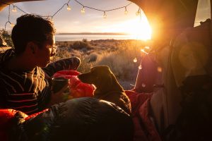 woman car camping with a dog while watching sunrise